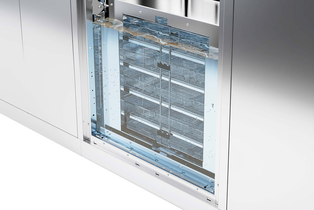 Sterilization equipment with an open chamber and multiple trays inside, surrounded by a sleek metal exterior.